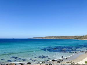 a beach with a person walking on the beach at The Lookout in Sennen