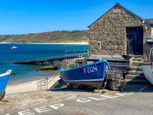 a blue boat sitting on the beach next to a building at The Lookout in Sennen