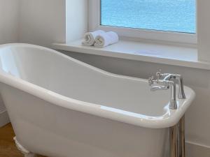a white bath tub in a bathroom with a window at The Lookout in Sennen