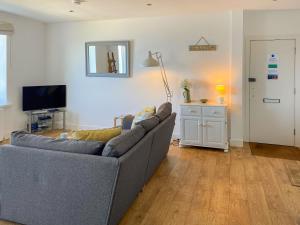 a living room with a gray couch and a television at The Lookout in Sennen +7 photos