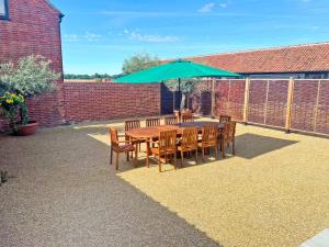 a table and chairs with an umbrella on a patio at Partridge Barn - Uk52217 in Corton