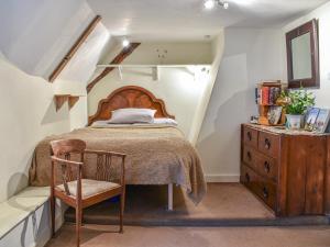 a bedroom with a bed and a chair and a dresser at Hoopers Farmhouse - Uk36307 in Tilshead +7 photos