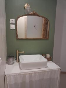a bathroom with a white sink and a mirror at La grange famille in Tournans