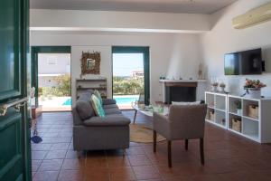 a living room with a couch and chairs and a tv at Villa Calliope Lardos in Lartos
