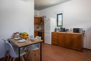 a kitchen with a table and chairs and a kitchen with a refrigerator at Villa Calliope Lardos in Lartos