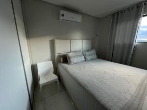 a small bedroom with a bed and a white chair at Suite Master Casa Luz in Garanhuns
