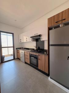 a kitchen with a stainless steel refrigerator and wooden cabinets at Magic House T5 -El Mansouria in Mansouria