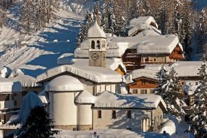 a building covered in snow next to a mountain at Hotel La Meridiana in Madesimo