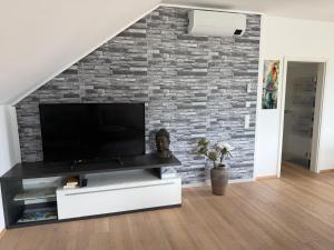 a living room with a tv on a brick wall at Ferienwohnung Moser in Pinsdorf