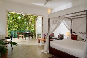 a bedroom with a bed and a balcony with a table at Ceylon Olive Galle in Galle +87 photos