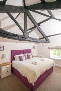 a bedroom with a large bed with a purple headboard at Netherby Hall in Carlisle