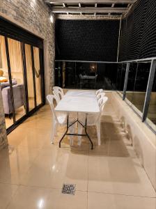 a white table and chairs in a room with windows at הפינה של פנינה במושבה - דירה משפחתית מהממת in Migdal