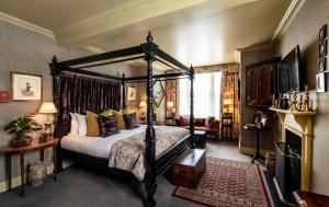 a bedroom with a four poster bed and a fireplace at The Loch Lomond Arms Hotel in Luss