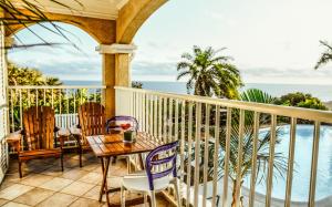 a balcony with a table and chairs and the ocean at Maison d'hôtes Villa des Mascareignes in Petite Île