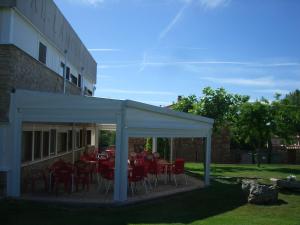 a patio with red tables and chairs under a white canopy at La Muralla in Retortillo de Soria