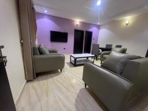 a living room with couches and a purple wall at Excellence Citizens Hotel and Resort in Ilorin