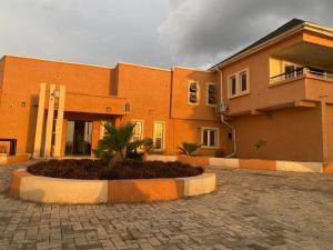 a large brick building with a palm tree in front of it at Excellence Citizens Hotel and Resort in Ilorin