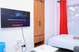 a bedroom with a bed and a tv on the wall at Onkundis Luxury Homes in Kiambu