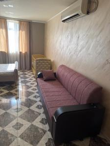 a living room with a purple couch and a chair at gest house in Pʼarakʼar