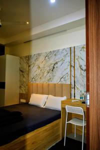 a bedroom with a bed and a table and a chair at Xsquare Hotel in Garubhāsa