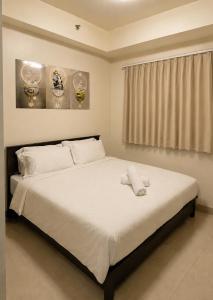 a bedroom with a bed with white sheets and a window at Shore 1 Tower D in Manila