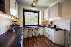 a kitchen with white cabinets and a large window at Szafran Home Spa in Korbielów