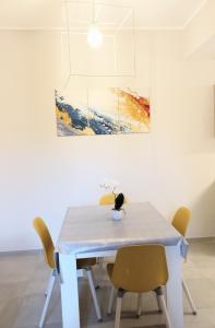 a dining room table with chairs and a painting at Mare&Sorrisi in Porto San Giorgio