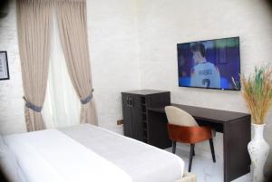 a bedroom with a bed and a desk and a television at De Grand Vale Hotel and Suite in Abuja