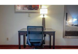a desk with a blue chair and a table with a lamp at Motel 6 Elkhart, IN in Elkhart