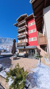 a hotel with a red building with snow on the ground at Romantic Charming Hotel Rancolin in Moena