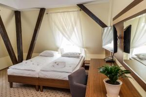 a bedroom with a bed and a desk and a tv at Fregata in Ełk
