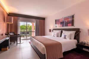 a hotel room with a large bed and a desk at Vila Gale Collection Praia in Albufeira
