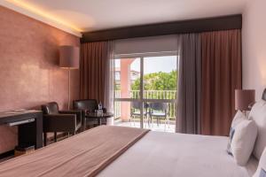 a hotel room with a bed and a balcony at Vila Gale Collection Praia in Albufeira +49 photos