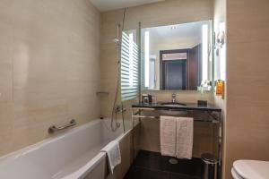 a bathroom with a bath tub and a sink at Vila Gale Collection Praia in Albufeira