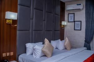 a hotel room with a bed with white pillows at De Grand Vale Hotel and Suite in Abuja +27 photos