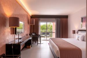 a hotel room with a large bed and a desk and a desk at Vila Gale Collection Praia in Albufeira
