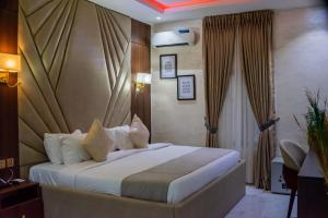 a hotel room with a bed with white sheets and pillows at De Grand Vale Hotel and Suite in Abuja