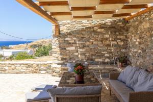 a patio with a table and chairs and a stone wall at Epavlis Petrou Siwtou in Tinos