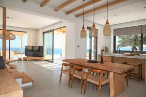 a kitchen and living room with a wooden table and chairs at Aethra Villa - Infinity Pool & Panoramic Sea View in Pefki