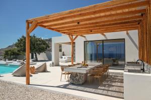 a patio with a table and chairs next to a pool at Aethra Villa - Infinity Pool & Panoramic Sea View in Pefki