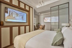 a bedroom with a bed and a flat screen tv at Glinter Barrio de las Letras - Apartments in Madrid