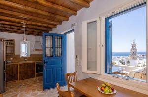 a kitchen with a blue door and a table with a bowl of fruit at Epavlis Petrou Siwtou in Tinos