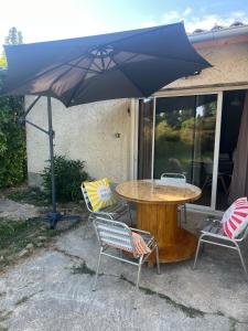 a table and chairs with an umbrella on a patio at Logement en campagne in Bédarrides