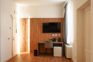 ein Zimmer mit einem Schreibtisch, einem Stuhl und einem Fernseher in der Unterkunft Hotel F52 in Parma + 17 Fotos