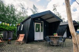 a black tiny house with a table and chairs at Kampeerhut met gedeeld sanitair in Wintelre +46 photos