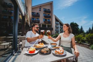 a man and woman sitting at a table with glasses of wine at Hotel FIS in Štrbské Pleso