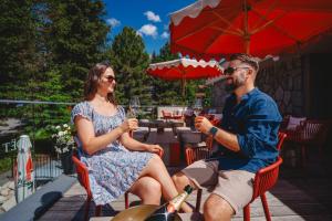 a man and a woman sitting in chairs under an umbrella at Hotel FIS in Štrbské Pleso +94 photos