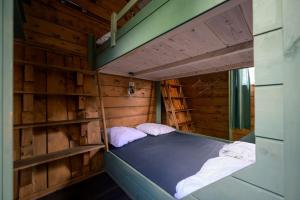 a bed in a wooden room with two pillows at Kampeerhut met gedeeld sanitair in Wintelre