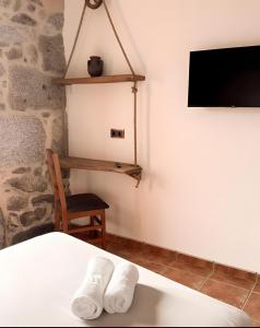 a bedroom with a bed and a chair and a tv at Casa As Fontes in Porqueirós