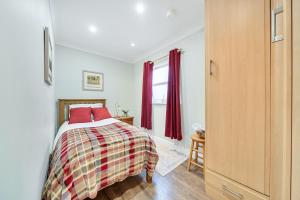 a bedroom with a bed with red pillows and a window at Central Ripon - Sleeps 3 - Garden - Pet Friendly in Ripon